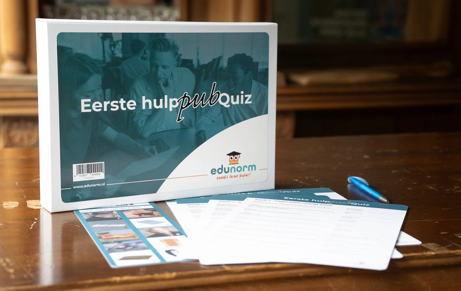 Doos en spelmateriaal van de Edunorm eerste hulp pubquiz, met gelamineerde kaarten en handleiding voor EHBO-trainingen.